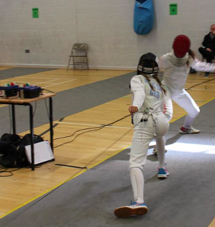 Two female foil fencers fighting on electric piste.
